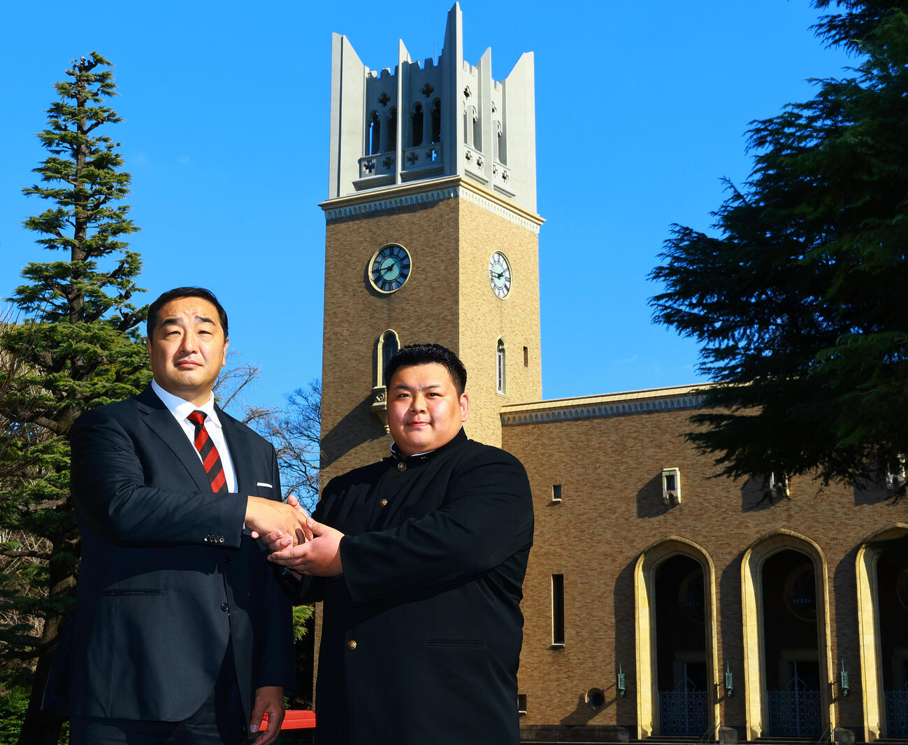 安治川部屋入門が決まり、早大大隈講堂を背に安治川親方（左）と握手する早大・川副（撮影・野上伸悟）
