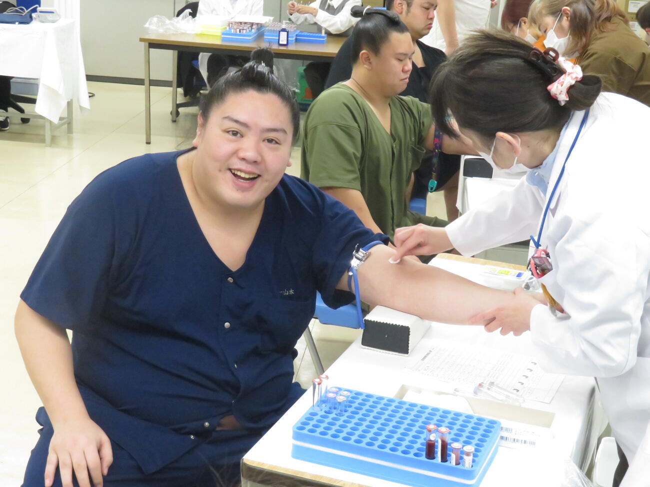 健康診断の採血で笑顔を見せる一山本。「初めて身長が190センチになりました。まげの調子が良かった」