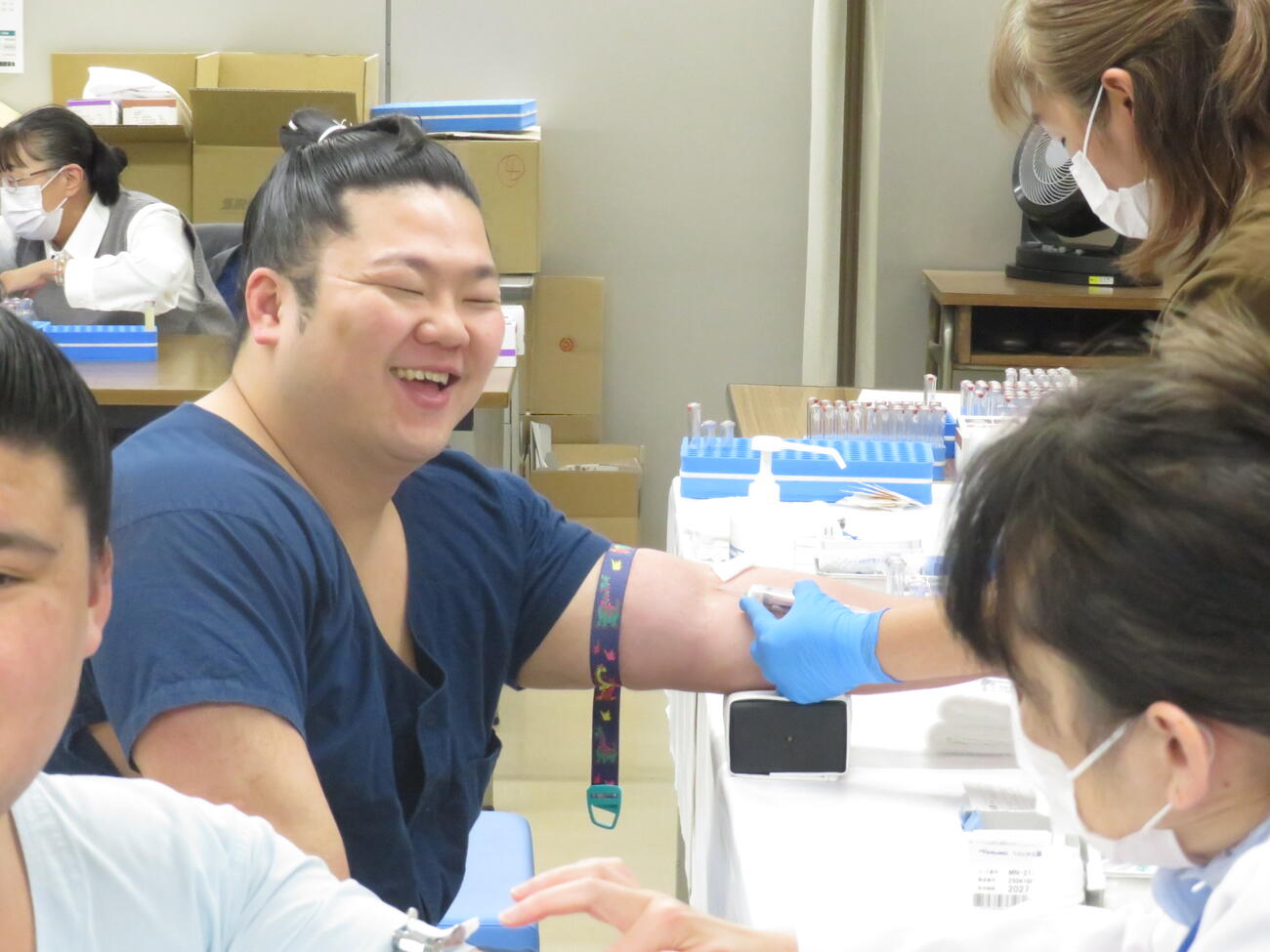 健康診断の採血で満面の笑みを見せる朝翠龍。同部屋の砂坂（手前）が、汗だくになっておびえている姿に思わず笑顔