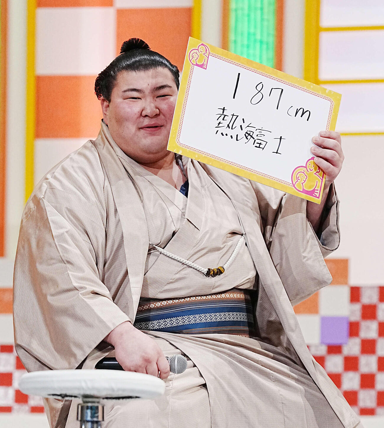 NHK福祉大相撲のお楽しみ歌くらべで身長を体重が上回っていることを明かされた熱海富士は用意されたフリップで恥ずかしそうに顔を隠す（撮影・小沢裕）