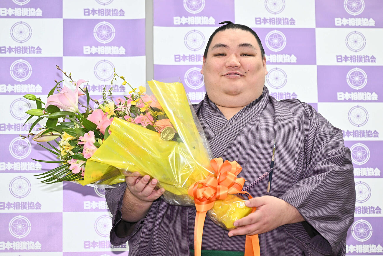 引退会見で花束を手に写真に納まる大翔鵬（撮影・滝沢徹郎）