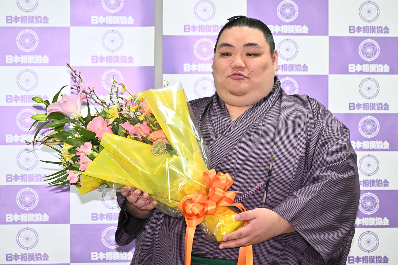 引退会見で花束を手に写真に納まる大翔鵬（撮影・滝沢徹郎）