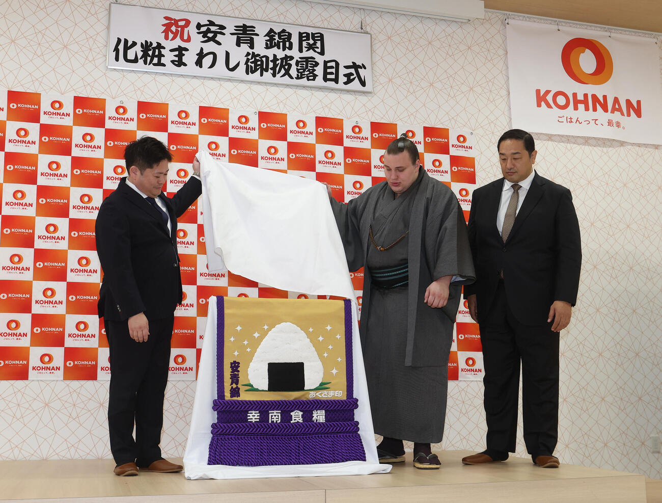 新しい化粧まわしをお披露目する、左から幸南食糧の川西孝彦代表取締役、安青錦、安治川親方（撮影・白石智彦）