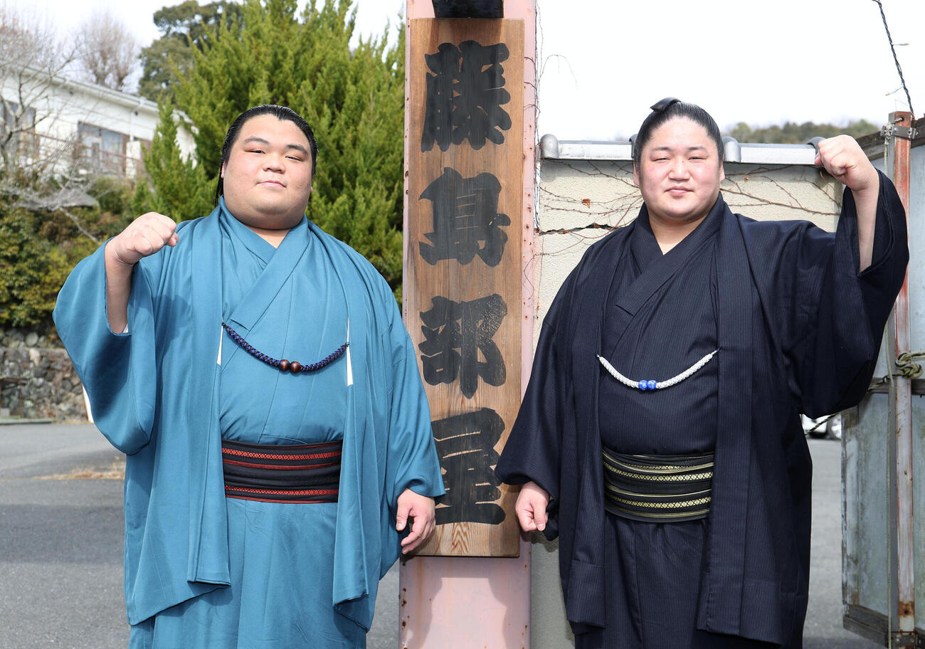 藤島部屋の看板前でガッツポーズする新入幕の藤凌駕（左）と藤青雲（撮影・白石智彦）