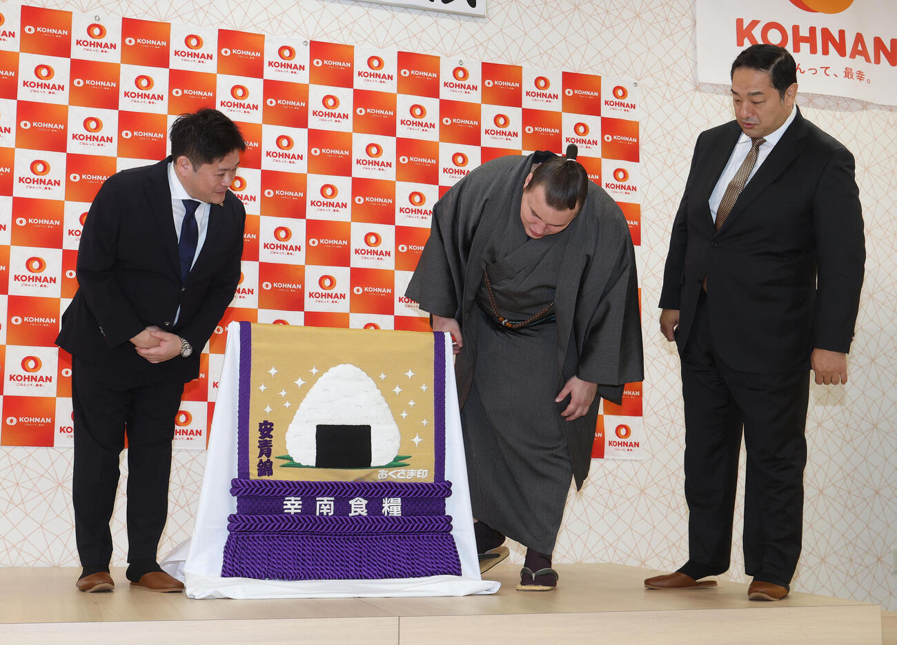 新しい化粧まわしを見る、左から幸南食糧の川西孝彦代表取締役、安青錦、安治川親方（撮影・白石智彦）