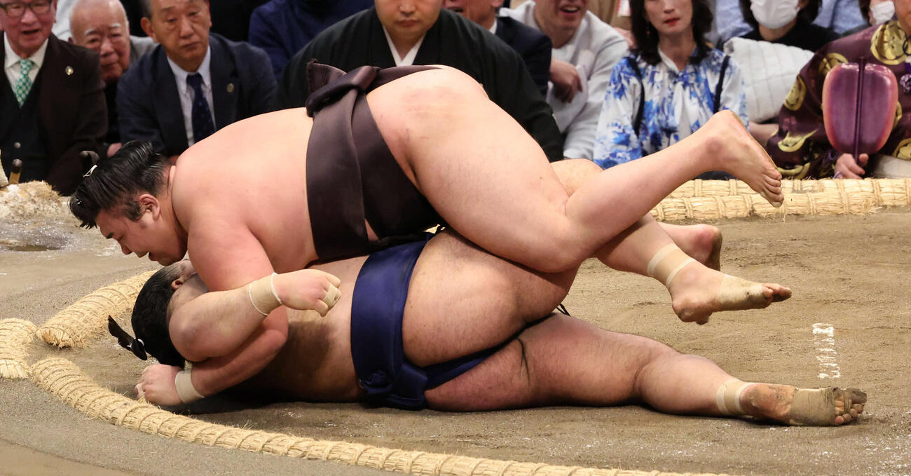 霧島はすくい投げで高安との元大関1敗対決を制し、勢い余って乗っかる（撮影・西尾就之）