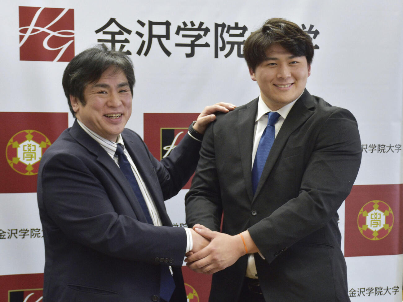 大相撲の追手風部屋への入門を発表し、金沢学院大の大沢恵介総監督（左）と握手する大森康弘（共同）