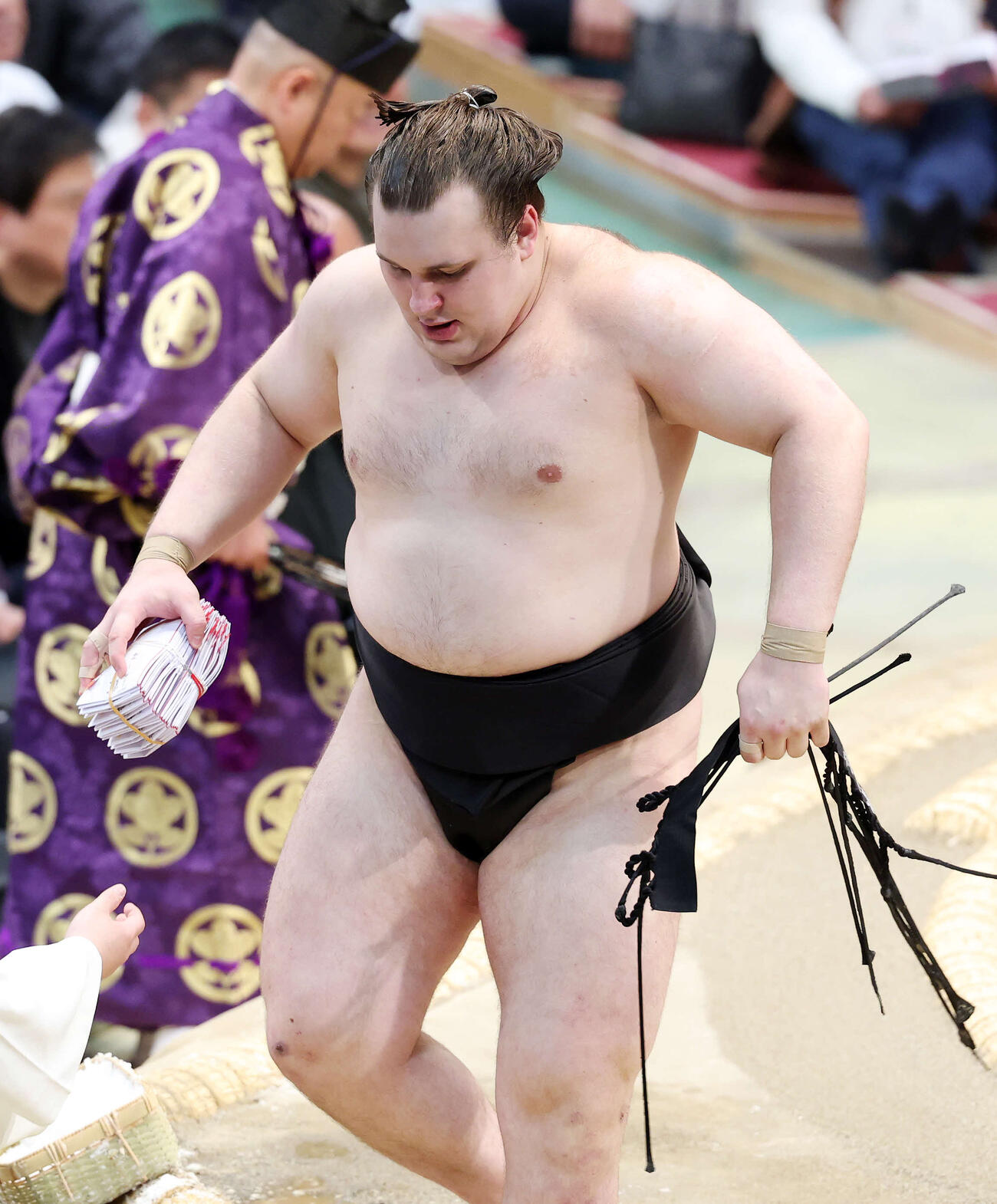 懸賞金の束を手に土俵を引き揚げる安青錦（撮影・鈴木正人）　