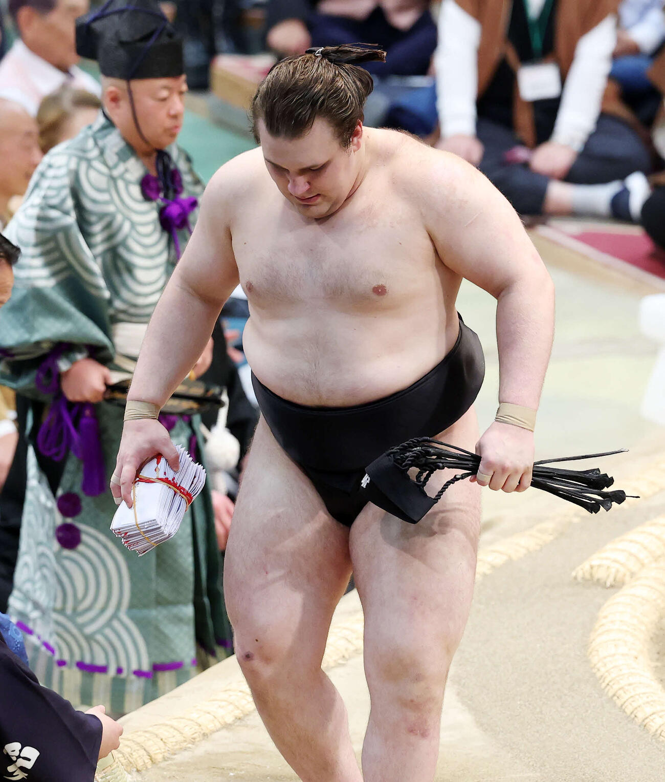 懸賞金の束を手に土俵を引き揚げる安青錦（撮影・鈴木正人）　
