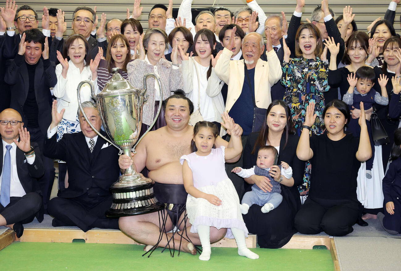 優勝賜杯を手に長女アヤゴーちゃんと万歳をし笑顔を見せる霧島。右はホラン夫人と長男トゥグドゥルくん