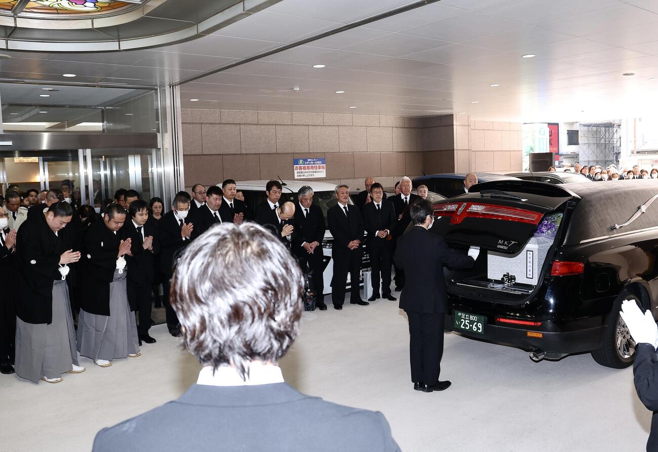霊きゅう車に運ばれた元大関若嶋津の日高六男さんのひつぎに手を合わせる一山本（左）と島津海（撮影・河田真司）