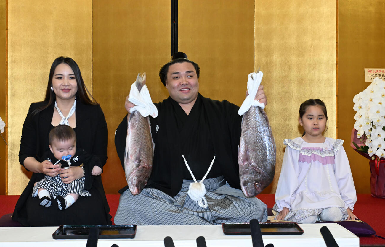 大関昇進の伝達を受け、ホラン夫人（左）とともにタイを掲げる霧島（撮影・和賀正仁）