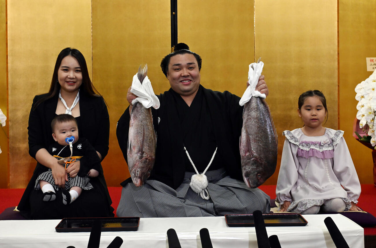 大関昇進の伝達を受け、ホラン夫人（左）とともにタイを掲げる霧島（撮影・和賀正仁）