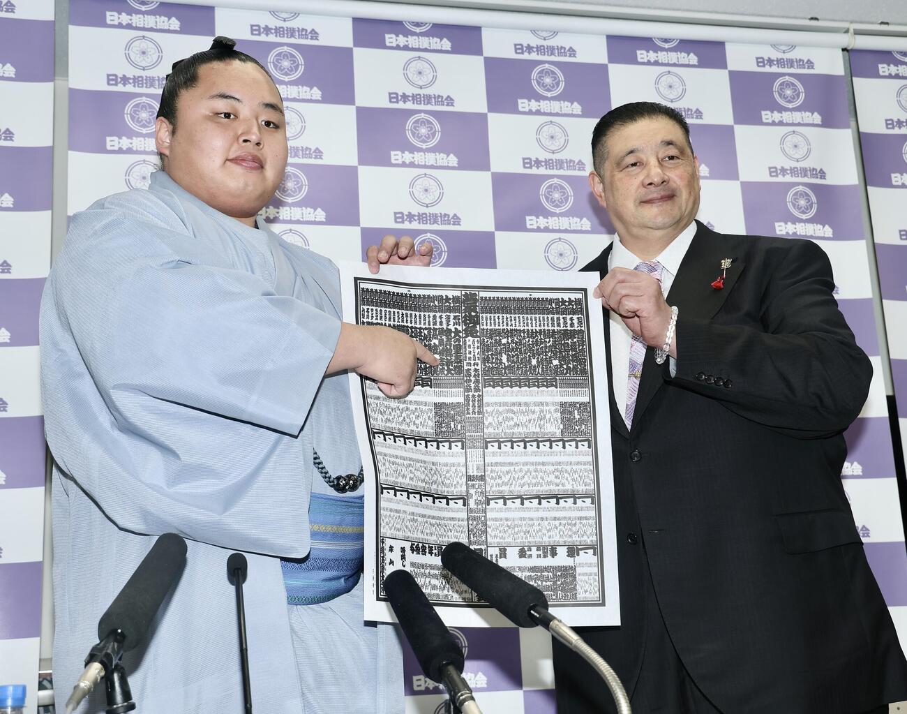 番付発表会見　番付表を手に写真に納まる琴勝峰（左）と佐渡ケ嶽親方＝2026年4月27日　