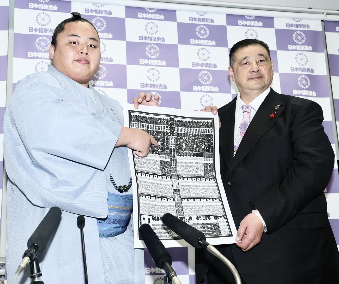 番付表を手に写真に納まる琴勝峰（左）と佐渡ケ嶽親方　