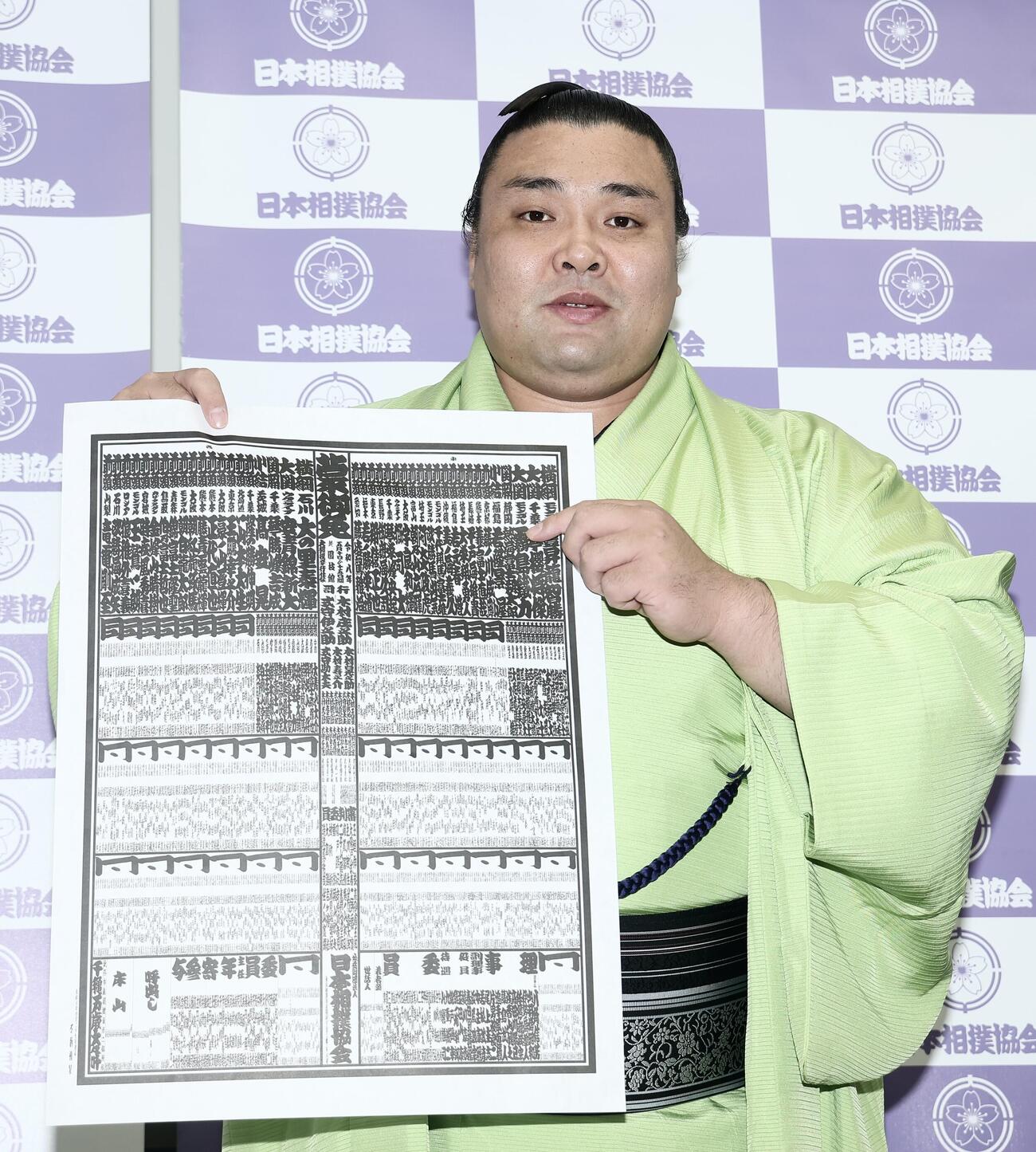 番付表を手に写真に納まる霧島（撮影・河田真司）　