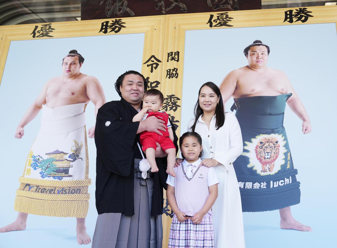 大相撲夏場所の優勝額贈呈式で長男トゥグドゥルくんを抱いて家族と記念撮影する霧島。右からホラン夫人、長女アヤゴーちゃん（撮影・小沢裕）
