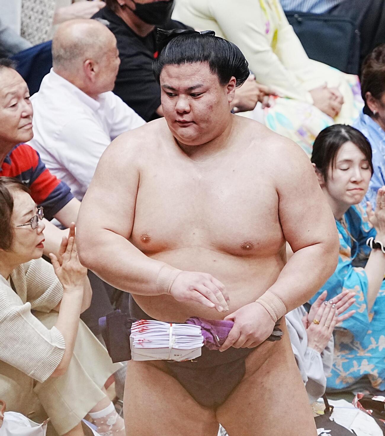 懸賞を手に花道を引き揚げる義ノ富士（撮影・小沢裕）
