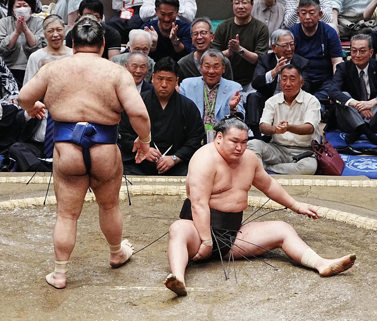 高安（左）に上手投げで敗れた豊昇龍は取組後に尻もちををつき、痛めたと思われる右太ももを手で押さえる（撮影・小沢裕）