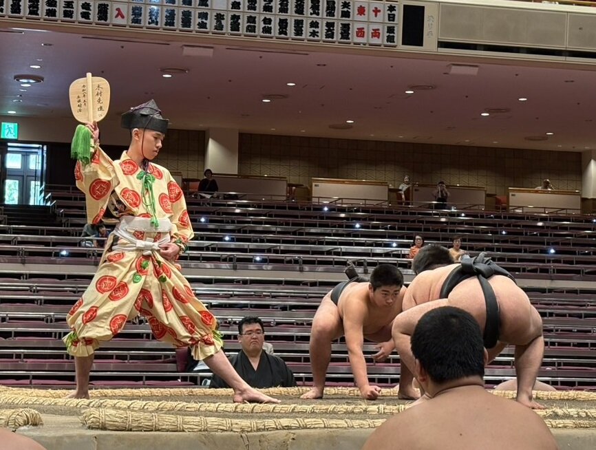 新しい軍配を持って土俵に上がった序ノ口格行司の木村先進（左）