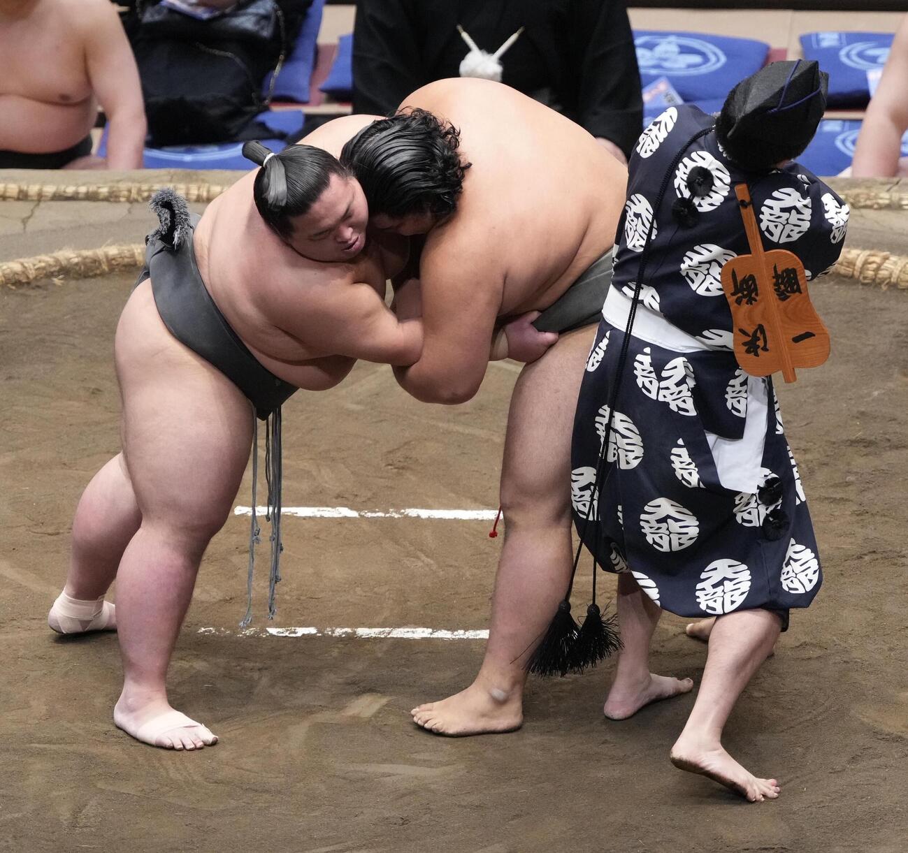 大相撲夏場所11日目　大斧（左）と竜鳳の一番で「まわし待った」をかけた行司の木村悟志（右）は緩んだ竜鳳のまわしを締め直す（撮影・小沢裕）　＝2026年5月20日