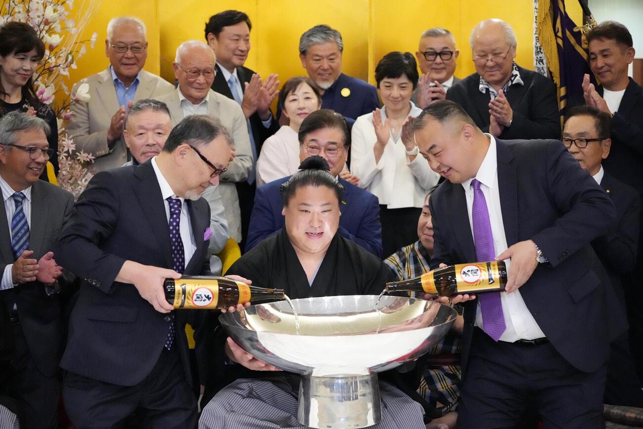 大相撲夏場所千秋楽　優勝祝賀会会場で後援会関係者から祝福を受けながらお祝いのお酒が注がれた銀杯を手にする若隆景（中央）。右は荒汐親方（撮影・小沢裕）