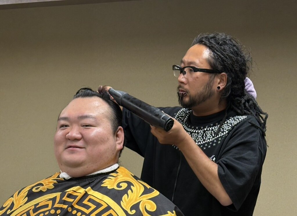 桐山親方（元関脇宝富士、左）を整髪する理容師の佐藤隆雄さん