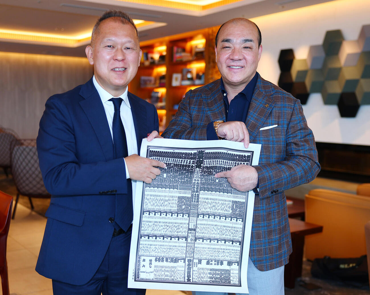 名古屋場所の番付表にある藤凌駕の名前を指す、にしたんクリニック西村誠司社長。左は日刊スポーツ佐々木一郎記者（撮影・野上伸悟）