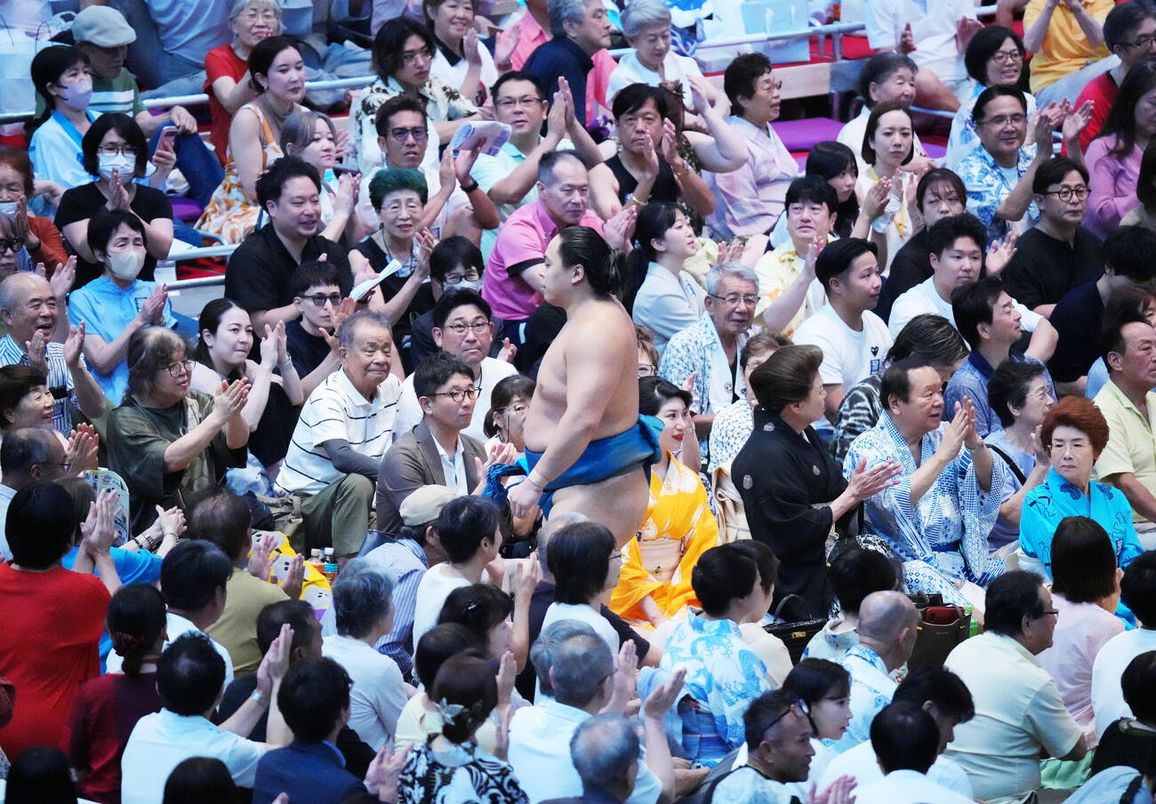 琴栄峰（中央）は観客の拍手を受けながら花道を引き揚げる（撮影・森本幸一）