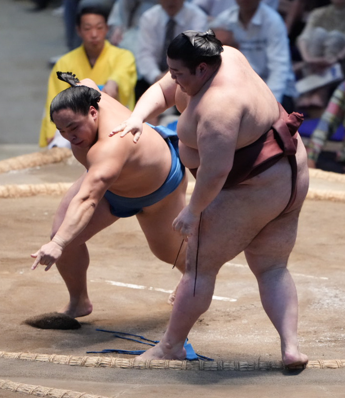 体勢を崩した琴栄峰（左）と右足が俵にかかった状態で身体を残す熱海富士（撮影・小沢裕）