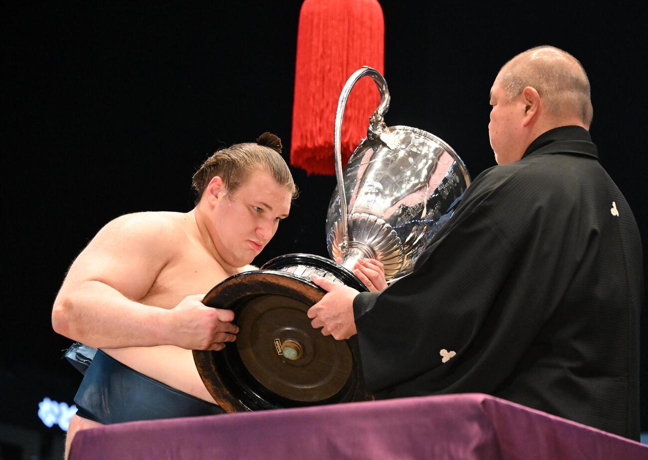 名古屋場所千秋楽　優勝し、表彰式で八角理事長（右）から賜杯を受け取る安青錦（代表撮影）