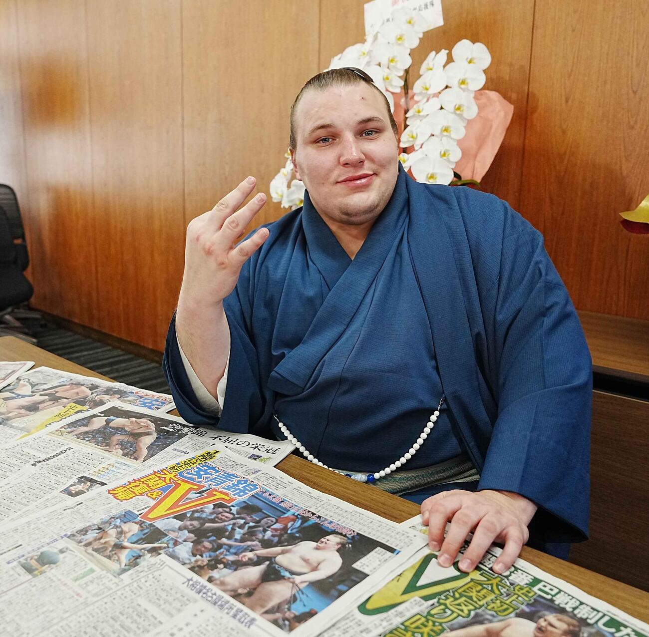 優勝一夜明け会見で新聞各紙を前に優勝回数「3」のポーズを決める安青錦（撮影・小沢裕）