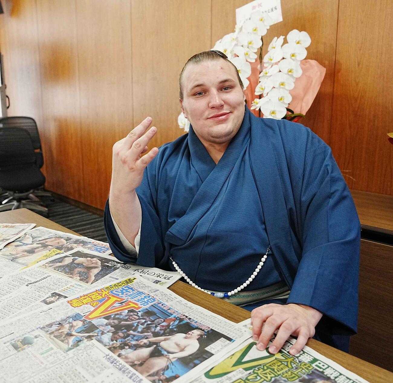 優勝一夜明け会見で新聞各紙を前に優勝回数「3」のポーズを決める安青錦（撮影・小沢裕）