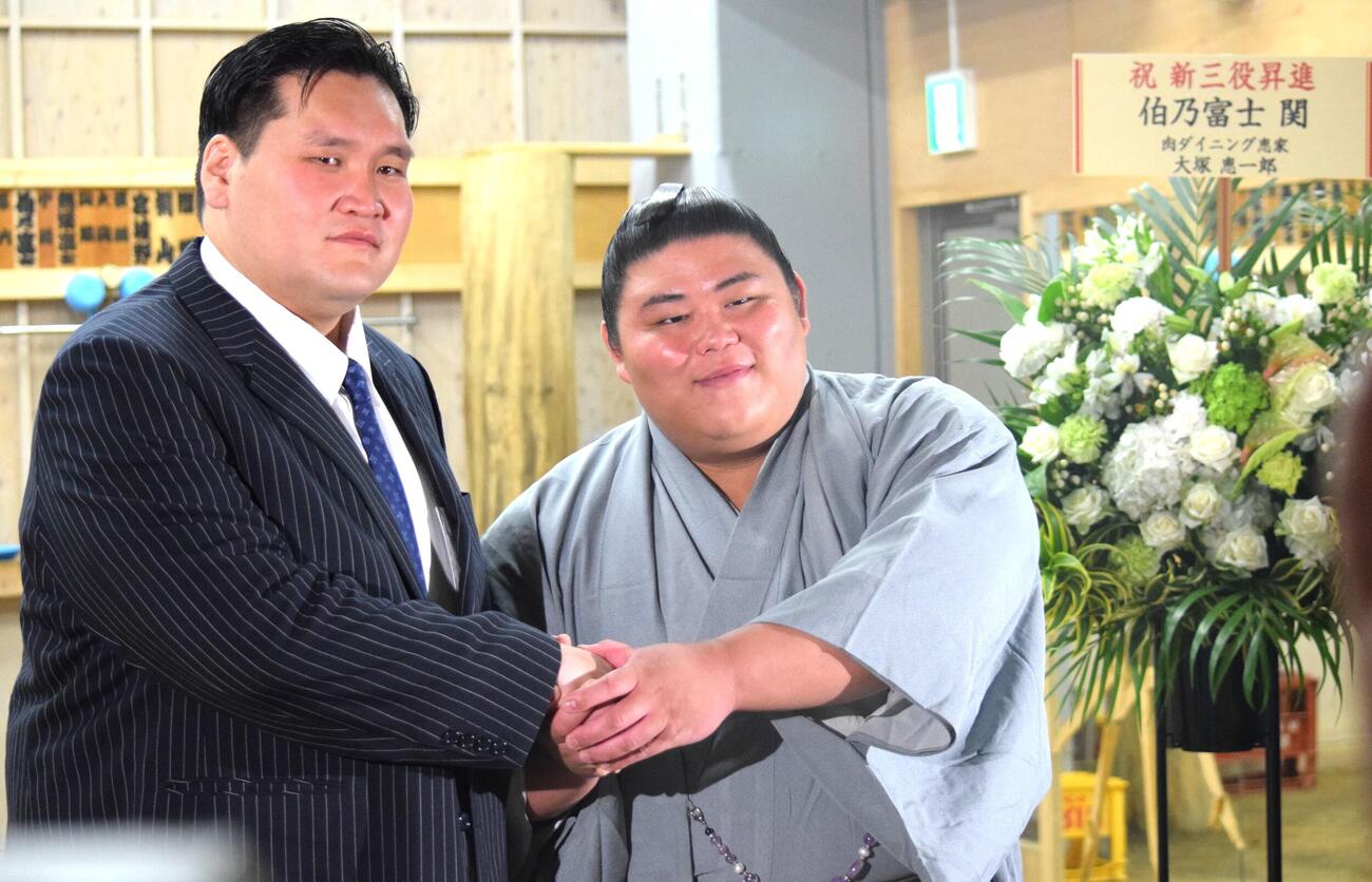 会見後に握手をする伯乃富士（右）と伊勢ケ浜親方