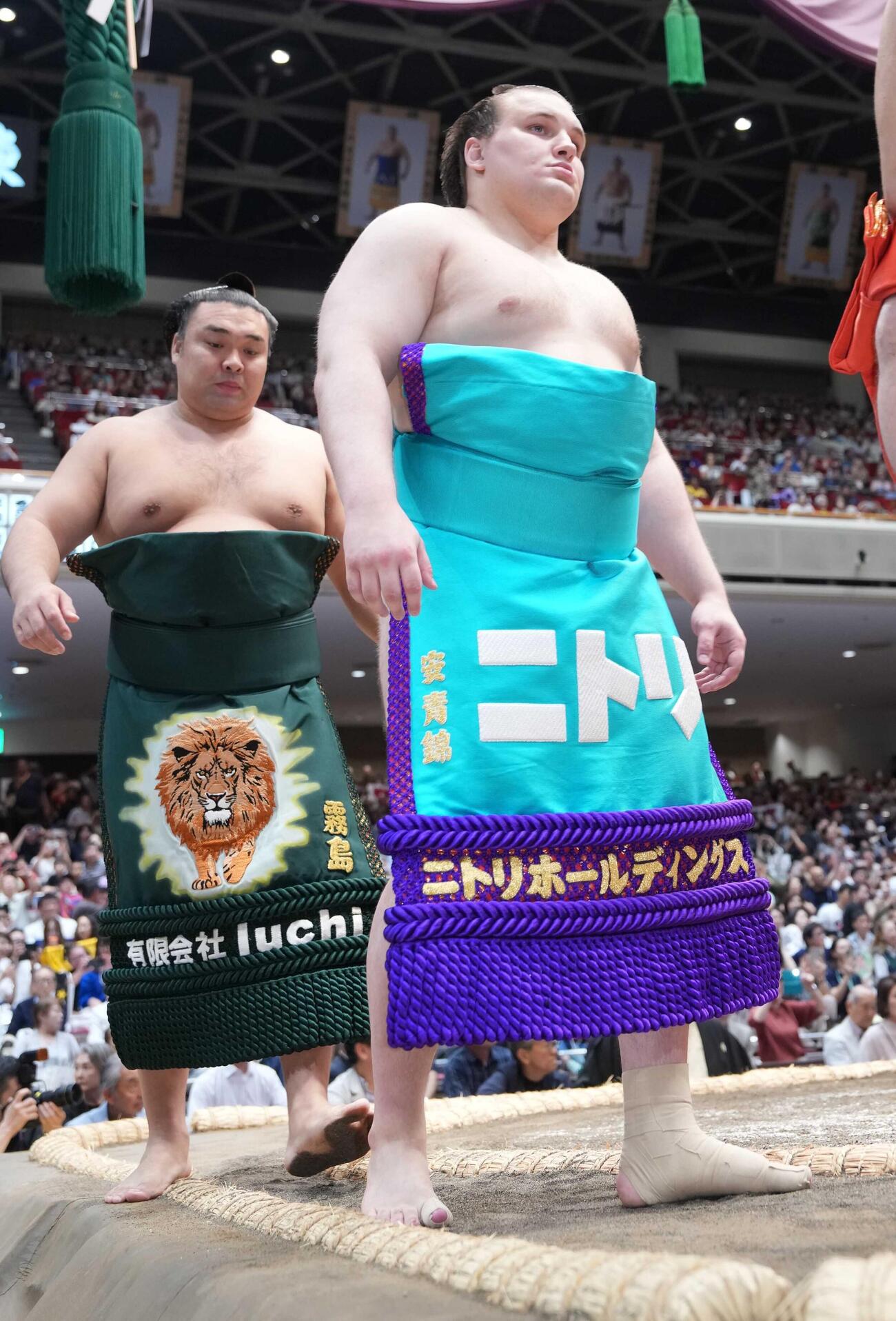 ニトリホールディングスの化粧まわしで幕内土俵入りに臨む安青錦。後方左は霧島（撮影・小沢裕）