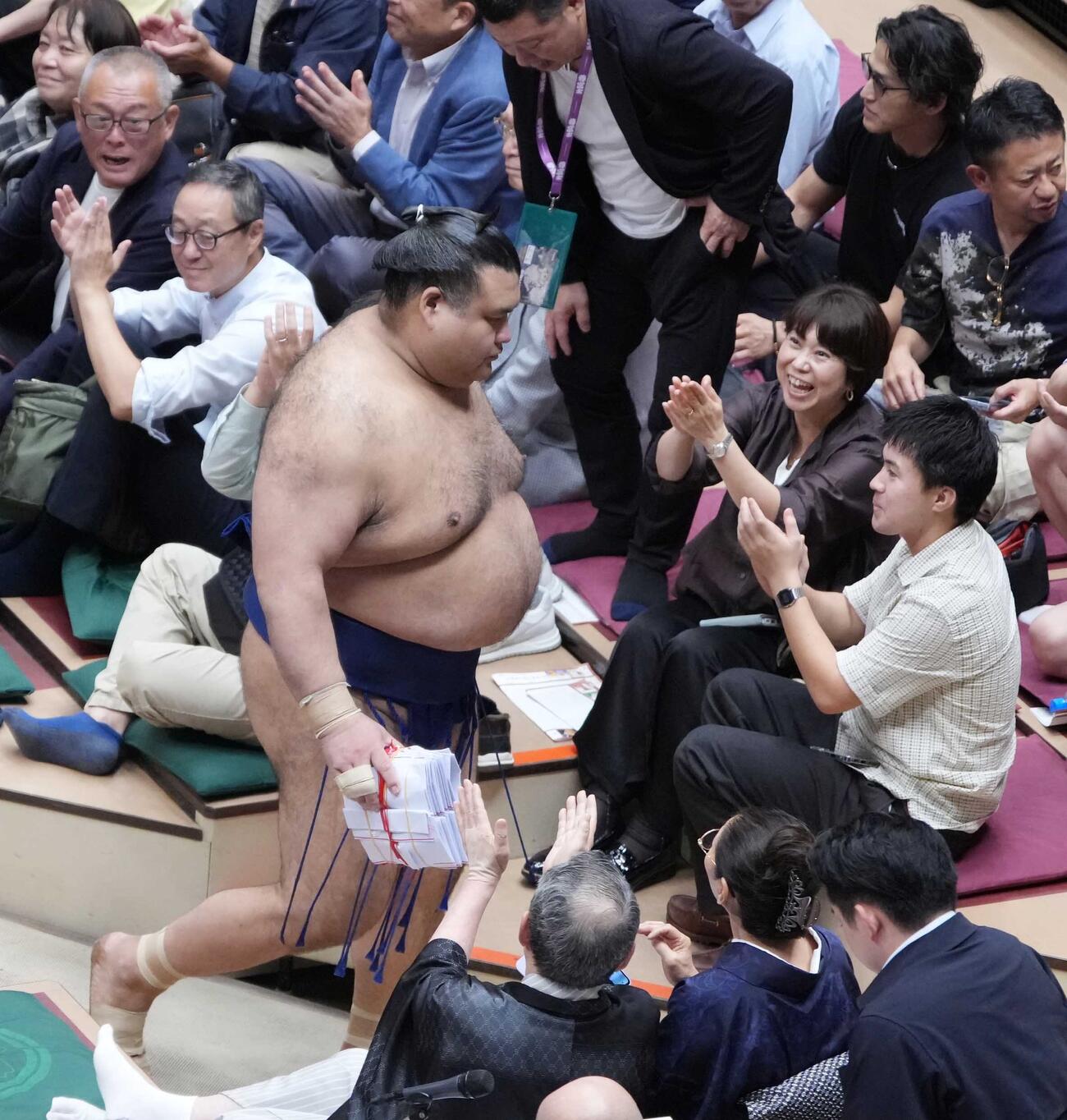 懸賞の束を手に花道を引き揚げる高安（撮影・小沢裕）