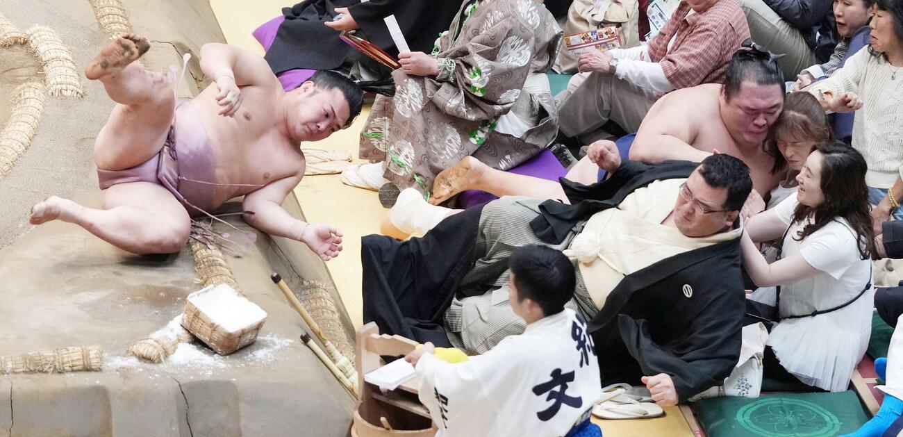 炎鵬（左）に押し出しで敗れ土俵下に落下した友風は溜まり席で観戦中の女性客と激突する（撮影・小沢裕）