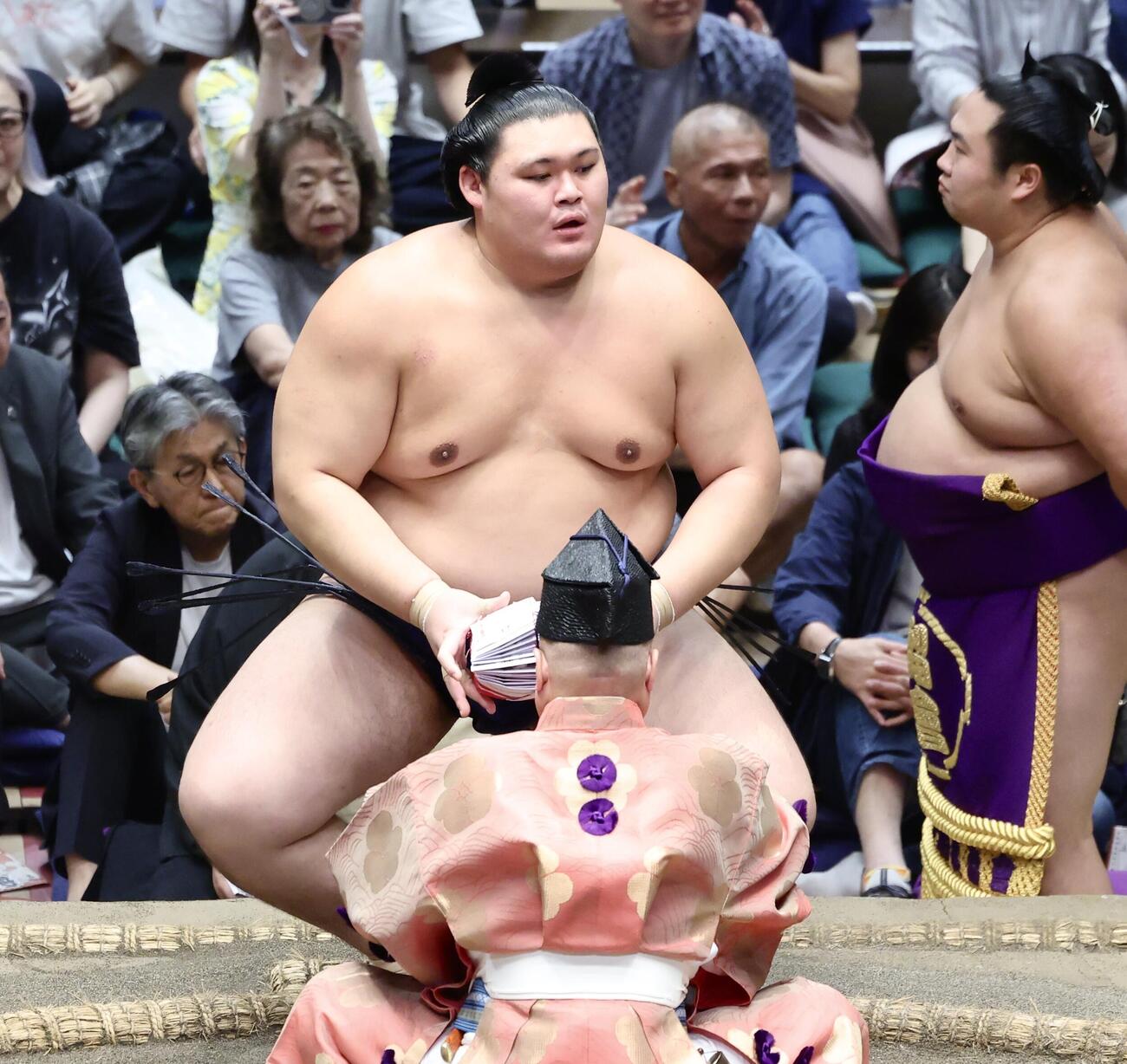隆の勝を寄り切りで破り、懸賞金の束を手に土俵から引き揚げる大の里（撮影・河田真司）