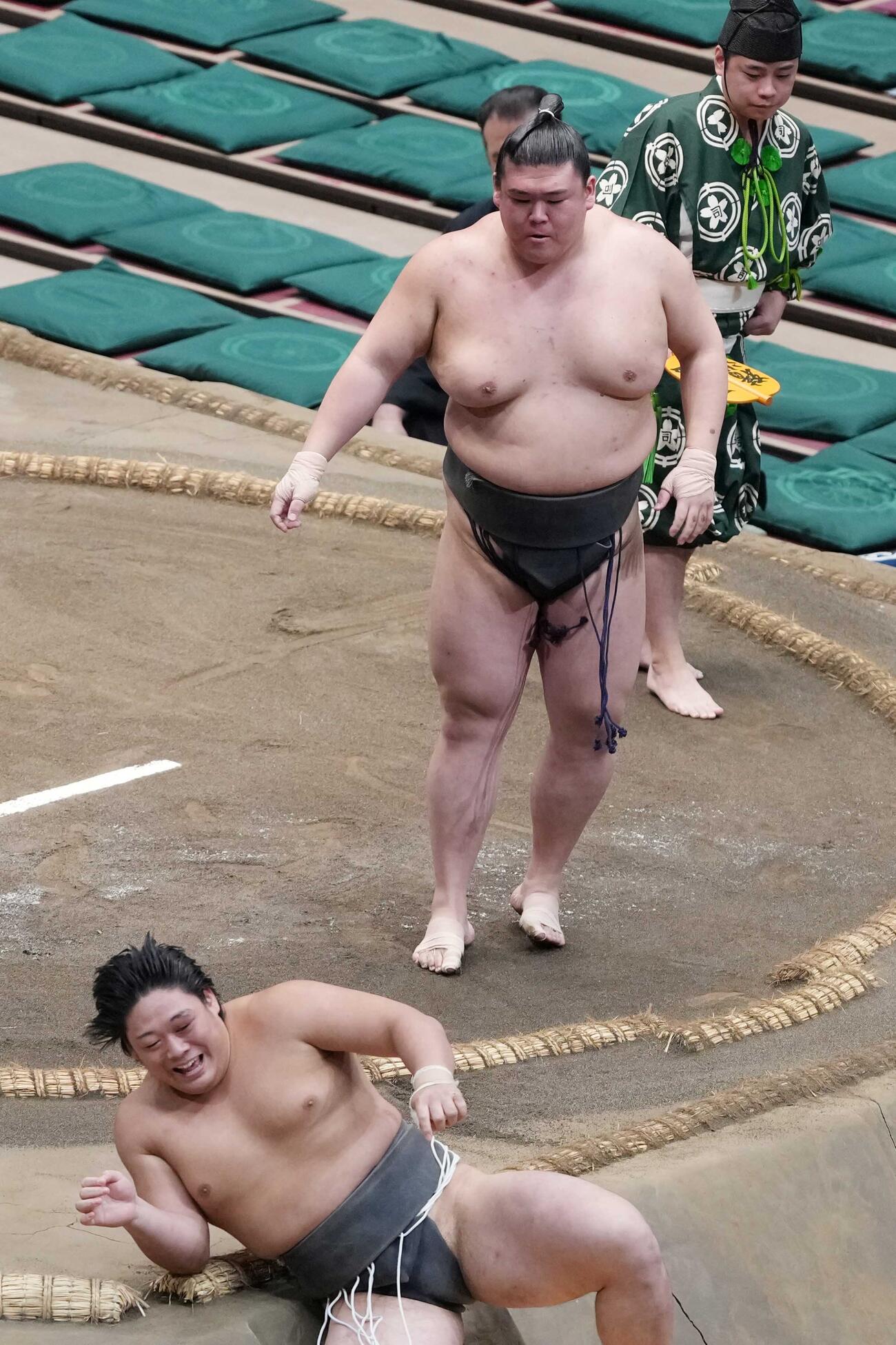 序二段の垣添（左手前）は三段目の納谷に送り倒しで敗れる。力の差を感じたのか苦笑いを浮かべていた（撮影・小沢裕）