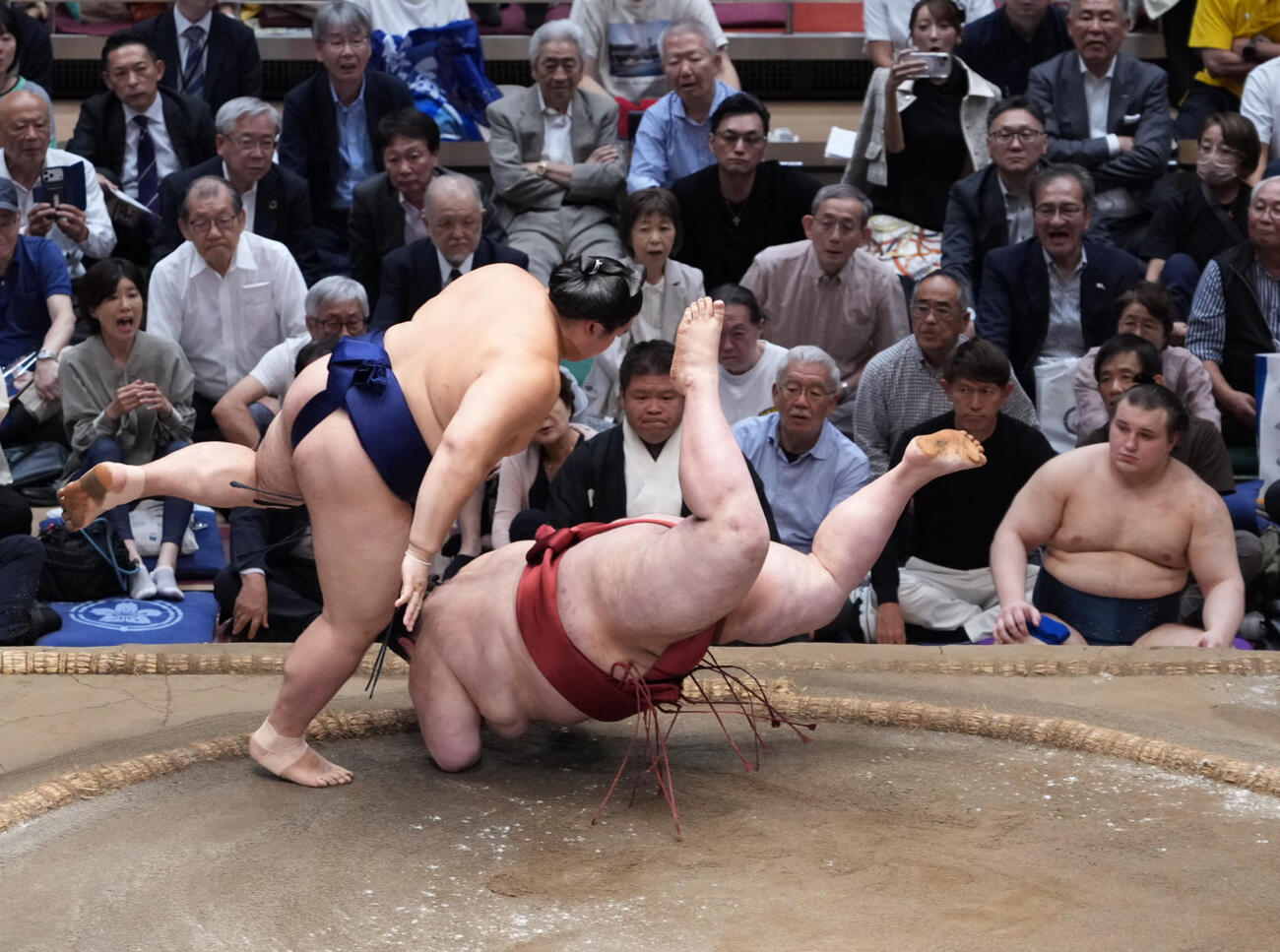大の里（左）は熱海富士を下手出し投げで下し1敗を死守する。右は土俵下控えの安青錦（撮影・小沢裕）