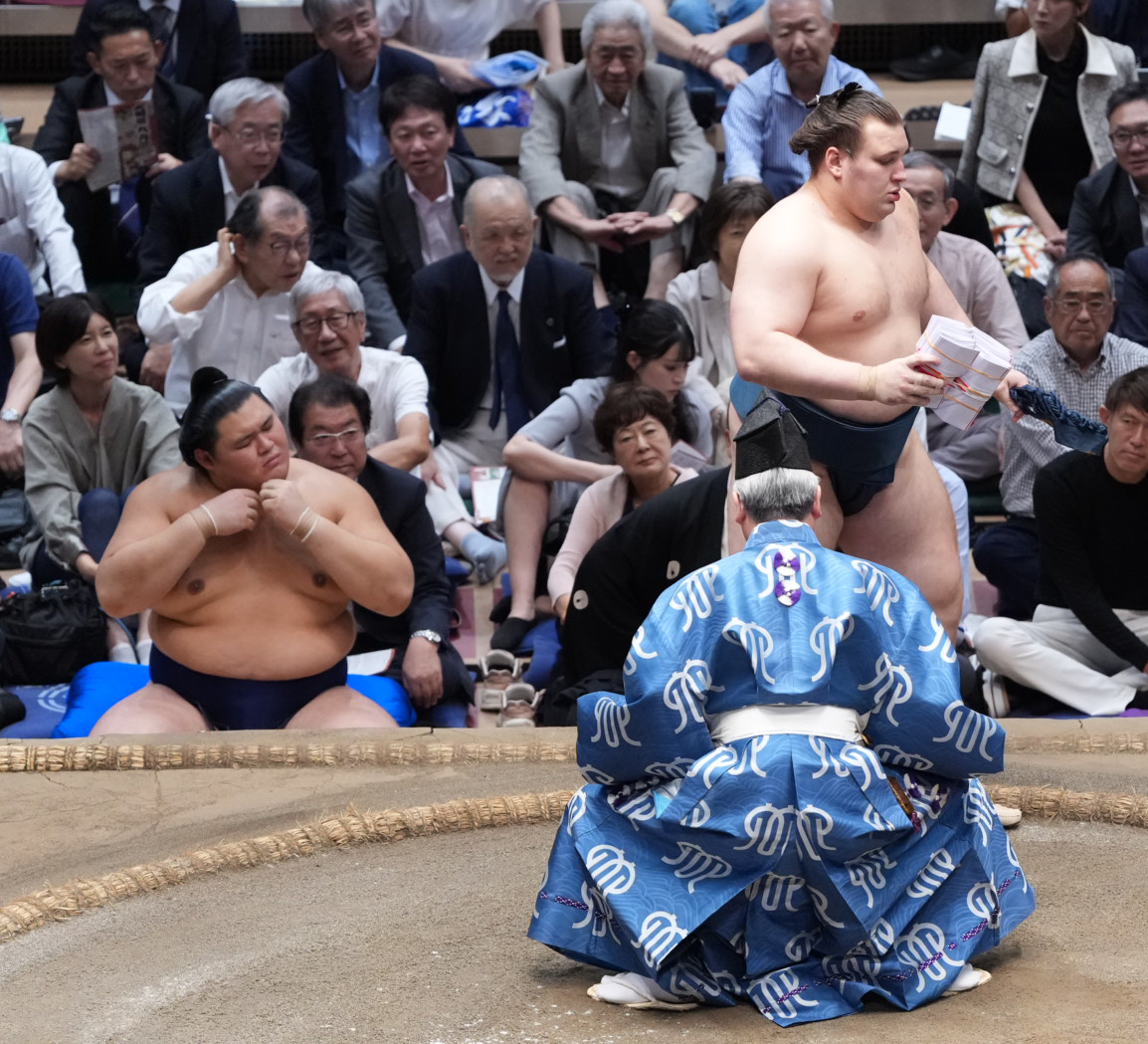 懸賞を手にする安青錦。左は土俵下控えの大の里（撮影・小沢裕）
