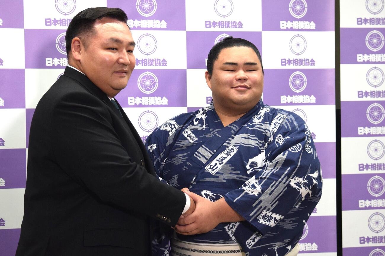 会見後に握手をする音羽山親方（左）と竜鳳