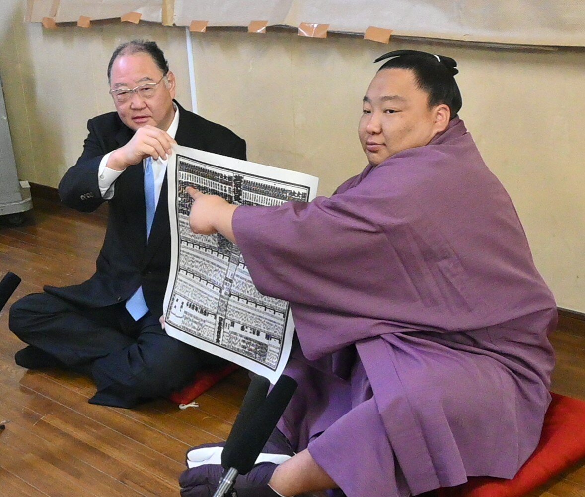 新入幕を果たした出羽ノ龍（右)は、出羽海親方と番付表を手にする