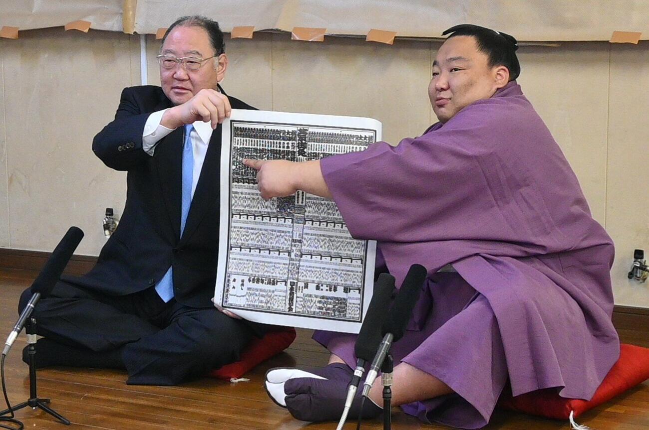 新入幕を果たした出羽ノ龍（右)は、出羽海親方と番付表を手にする
