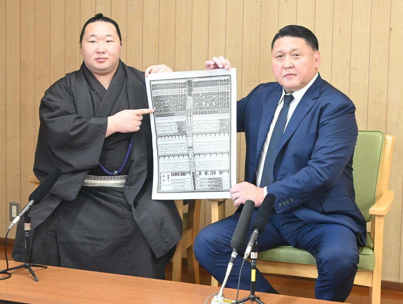 新入幕を果たし番付表を手にする旭海雄（左）と大島親方（撮影・飯岡大暉）