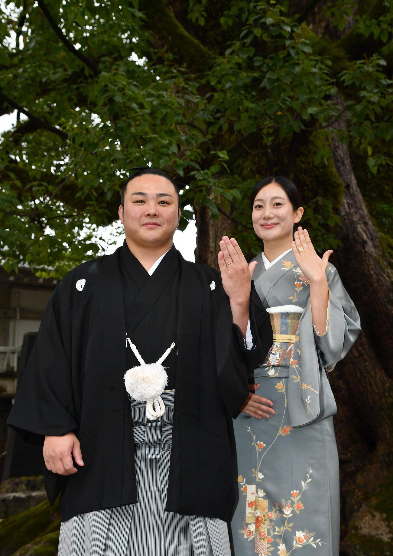 天然記念物の大樟の前で指輪を見せる炎鵬（左）と美希夫人（撮影・岩下翔太）