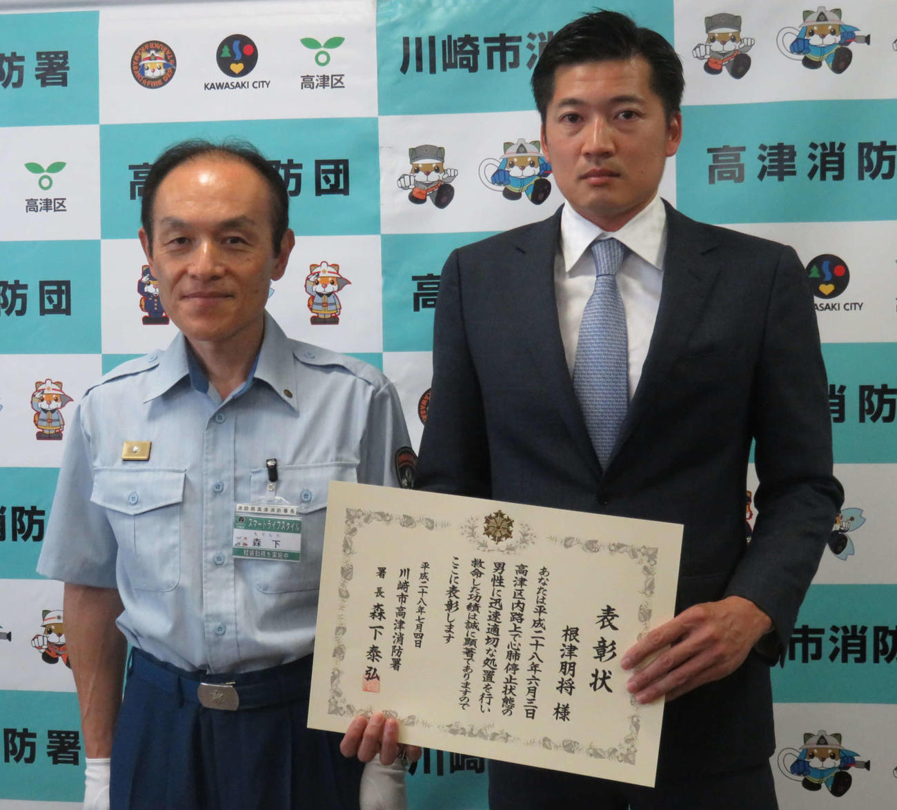 16年7月、川崎市高津消防署の森下署長（左）から人命救助の感謝状を贈られた巨人根津朋将トレーナー