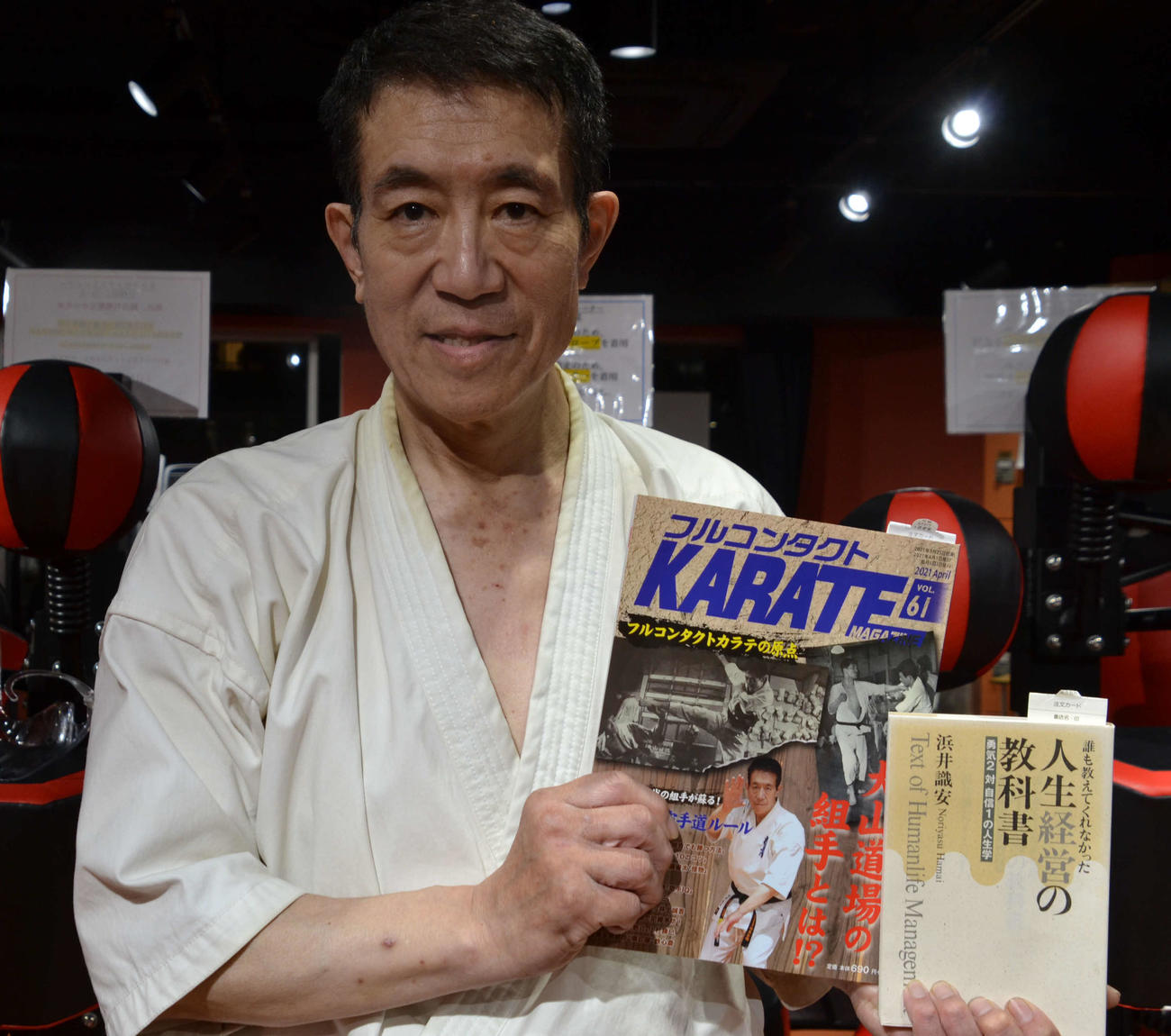 「KARATE VOL．61」と自著「人生経営の教科書」を手にする浜井代表