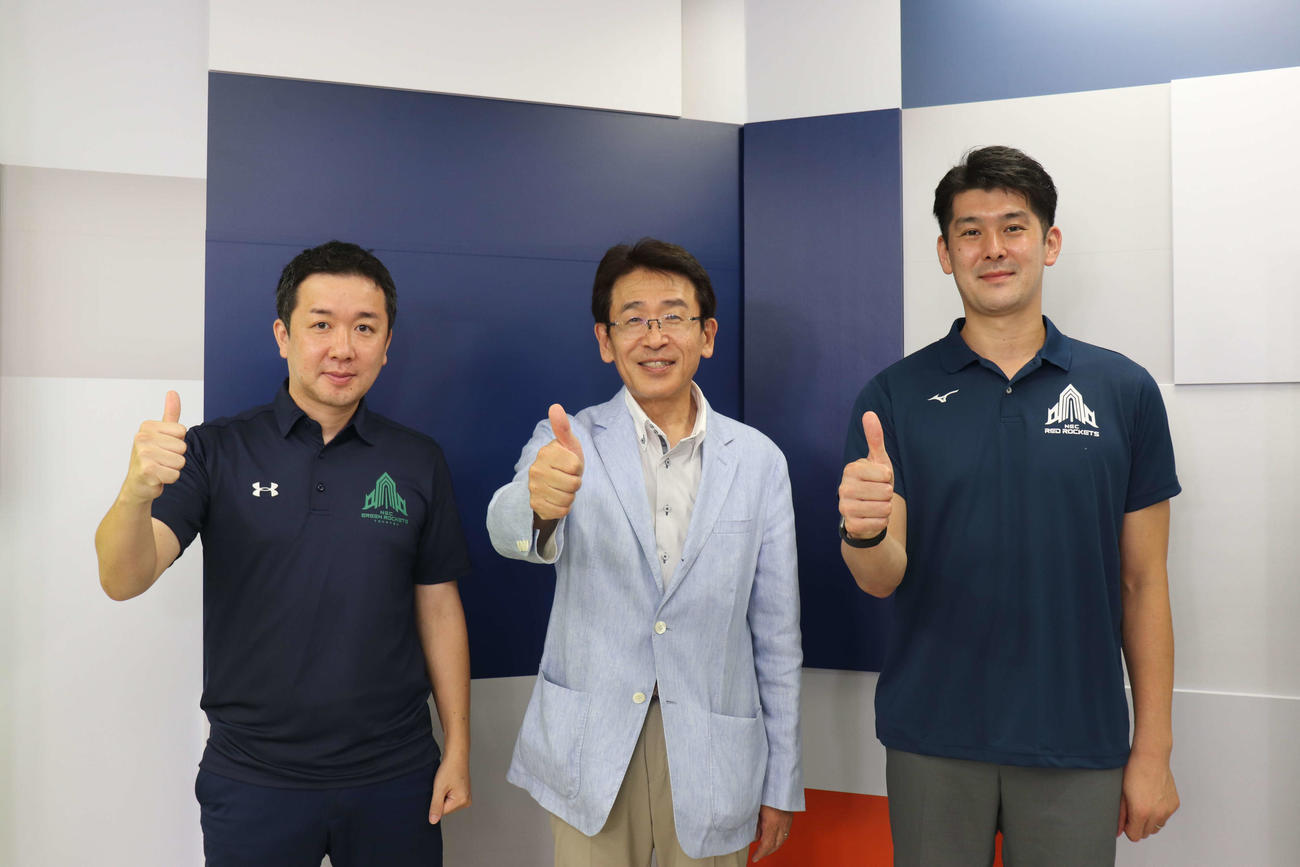 新体制の会見を行った左から梶原健スポーツビジネス推進本部本部長、松木俊哉執行役員常務、金子隆行監督（写真・エンブレムはNECレッドロケッツ提供）