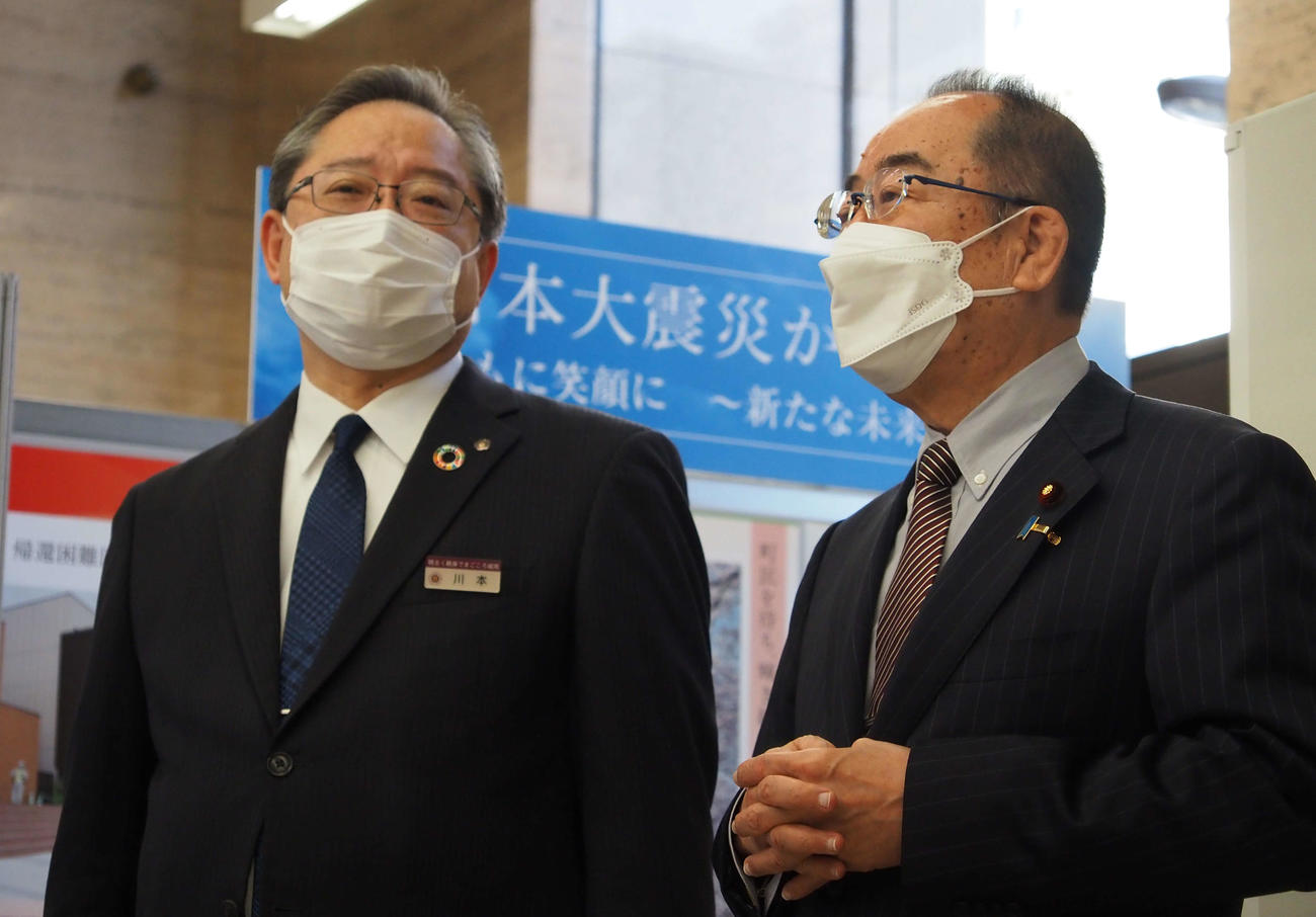 西銘恒三郎復興大臣（右）に展示内容を説明する川本理事長